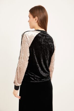 עורף בחורה בלבוש נוח מבדי קטיפה בצבעי ורוד ושחור.