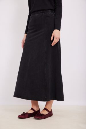 גיבנת אופנתית לנשים עם חצאית ג'ינס שחורה ונעלי בלט סרוגות צבע בורדו.